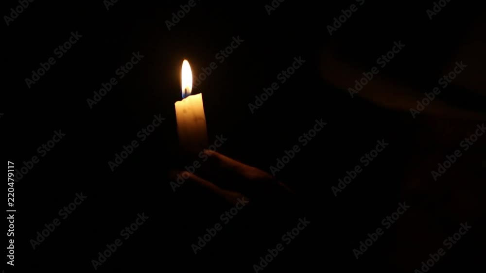 Lit candle held by hand in complete darkness Lit candle held by hand in complete darkness