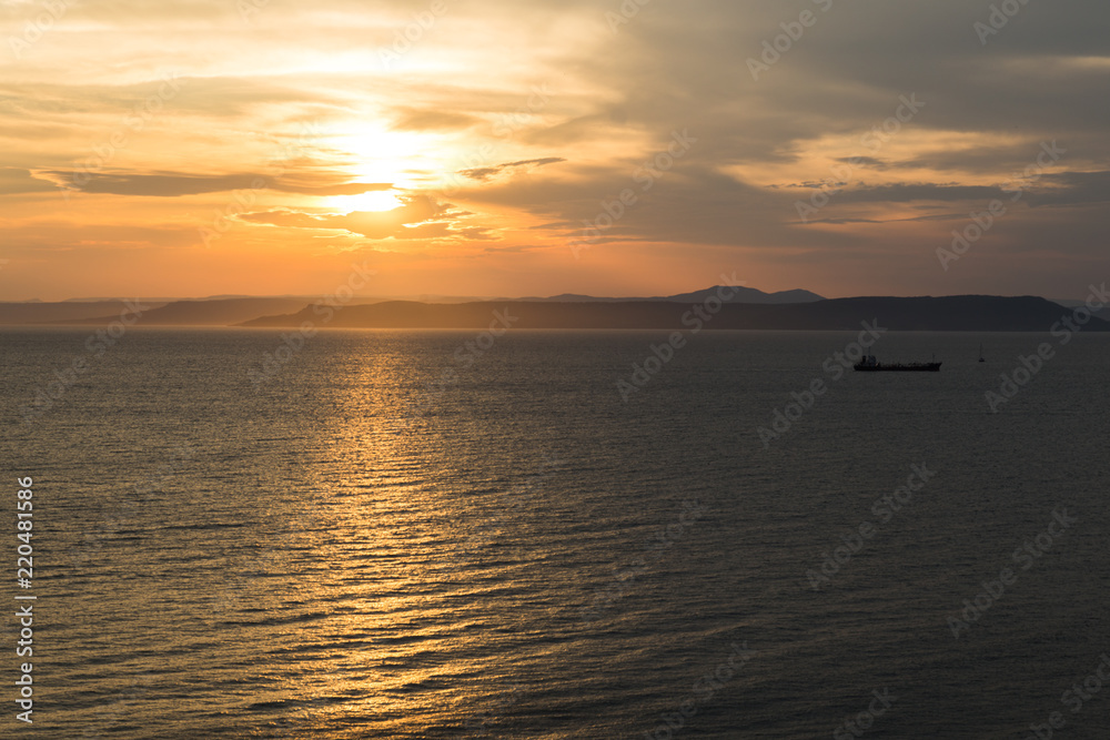 Beautiful sunset view over the sea and tanker ship silhouette