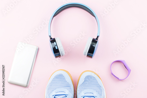 Woman sneakers, headphones, fitness tracker and running clothes on pastel background. Sport fashion concept. Flat lay