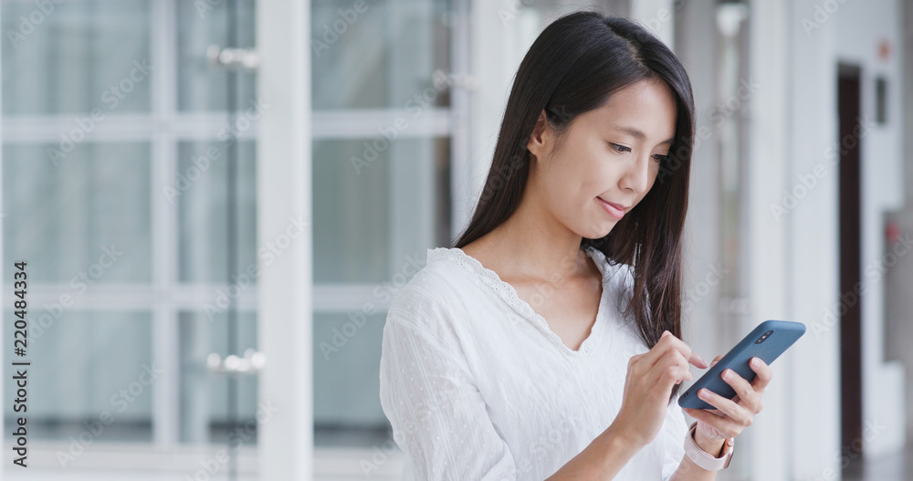 Woman looking for app on cellphone inside shopping mall