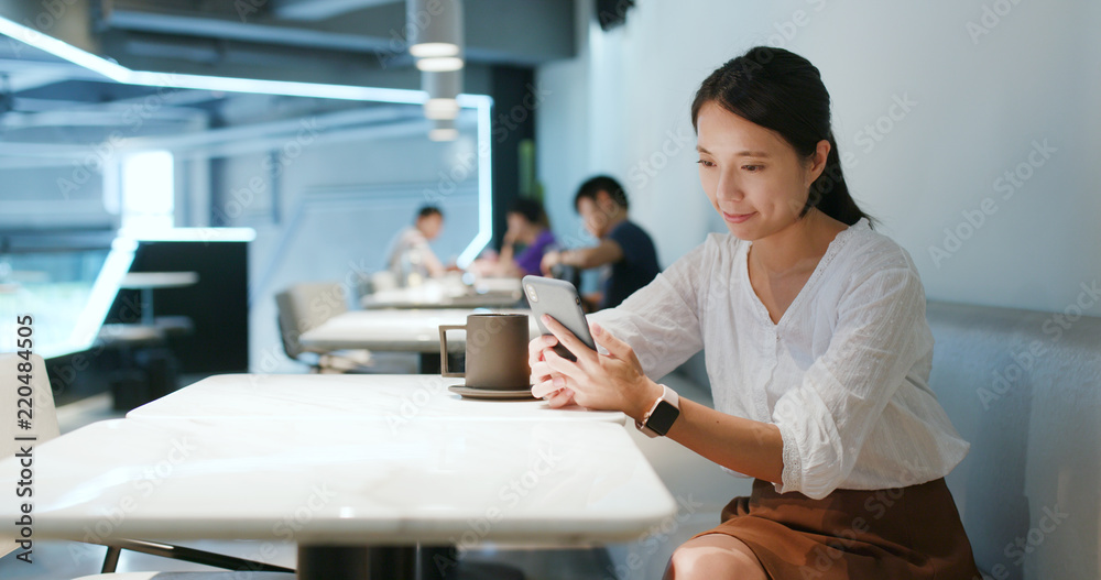 Obraz premium Woman look at mobile phone in the coffee shop