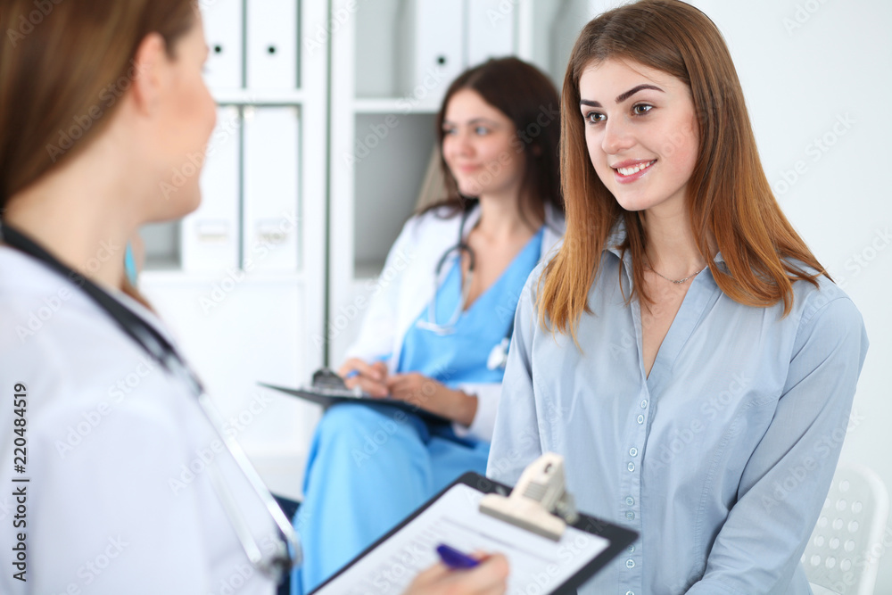 Happy smiling female patient with her doctor at clinic or hospital. Medicine and health care concept
