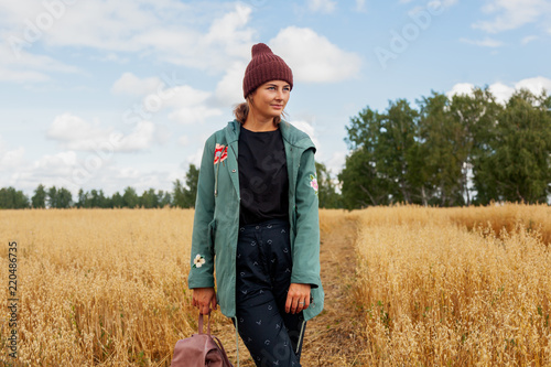 Outdoor fashion photo of young beautiful woman in golden field in warm autumn winter. Cozy autumn coat