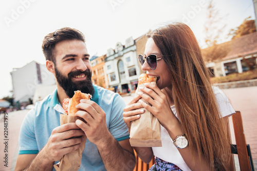 Young couple is eating sandwiches and having a great time
