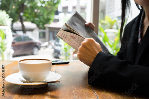 Attractive young business woman reading a newspaper at coffee cafe