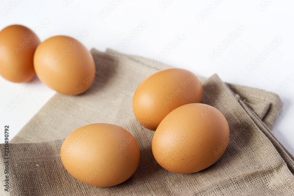 Brown chicken eggs on burlap on a white background Brown chicken eggs on burlap on a white background