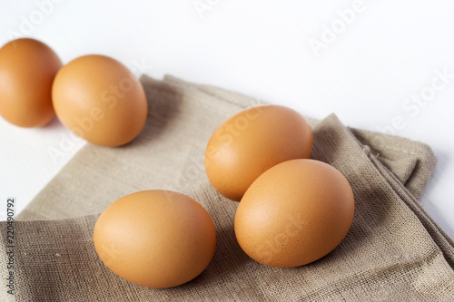 Brown chicken eggs on burlap on a white background