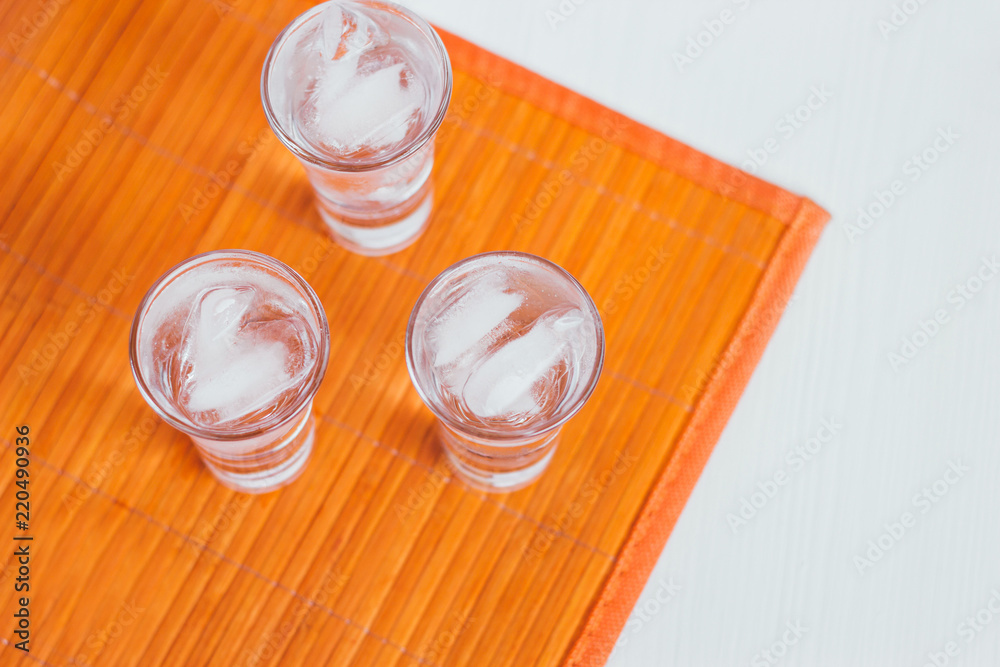 Vodka shots with ice on a white and orange background Vodka shots with ice on a white and orange background