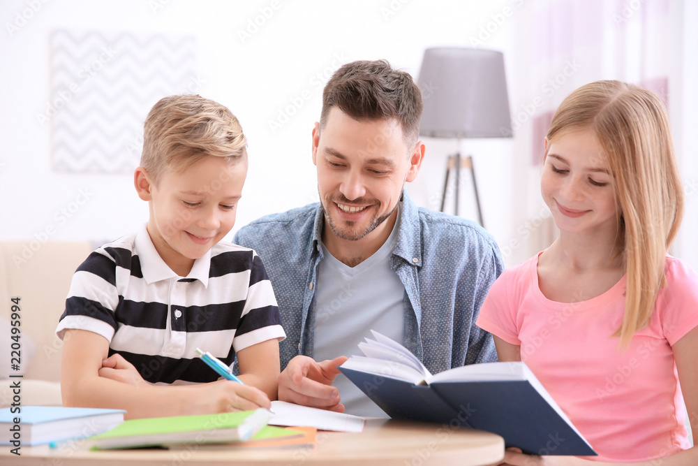 Cute little boy doing homework with father and sister Cute little boy doing homework with father and sister
