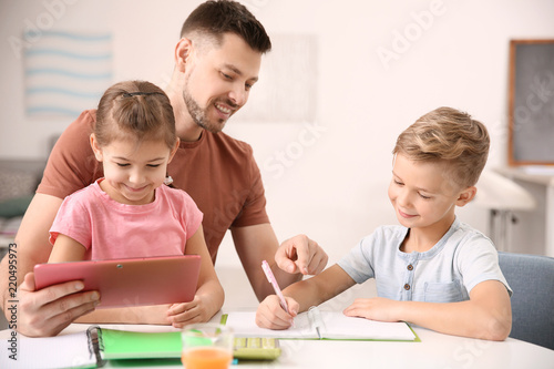 Cute little children doing homework with father