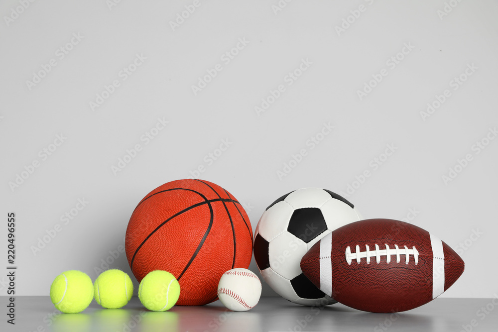 Different sport balls on table against color background. Space for text