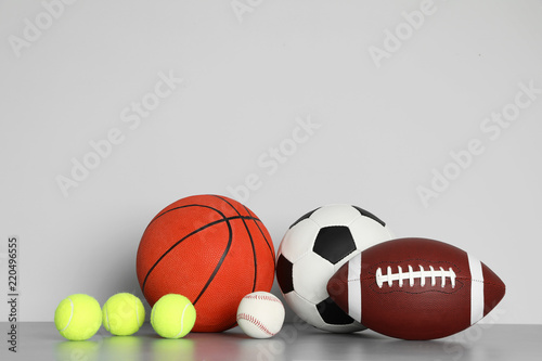 Different sport balls on table against color background. Space for text