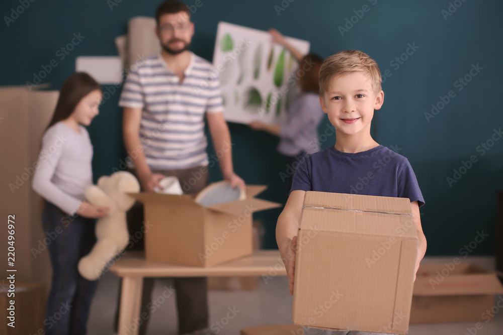 © Africa Studio - Cute child holding box while his family packing belongings on background. Moving day © Africa Studio - Cute child holding box while his family packing belongings on background. Moving day