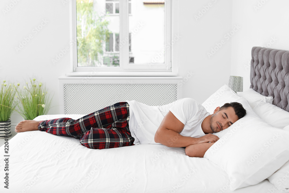 Young man sleeping on bed with soft pillows at home Young man sleeping on bed with soft pillows at home