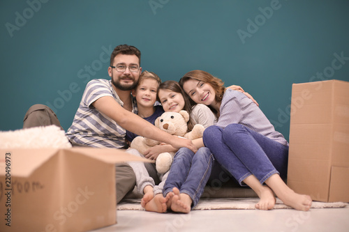 Couple with children sitting near boxes indoors. Happy family on moving day © Africa Studio