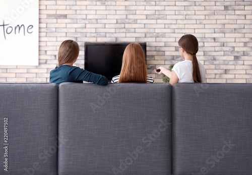 Young women watching TV at ...