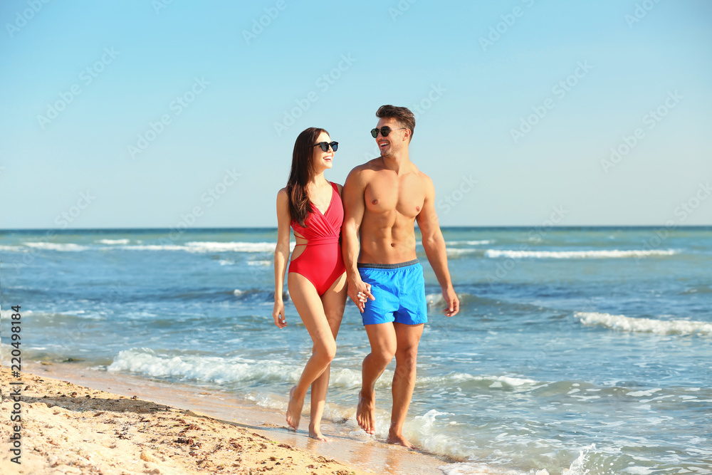 Happy young couple walking together on beach Happy young couple walking together on beach