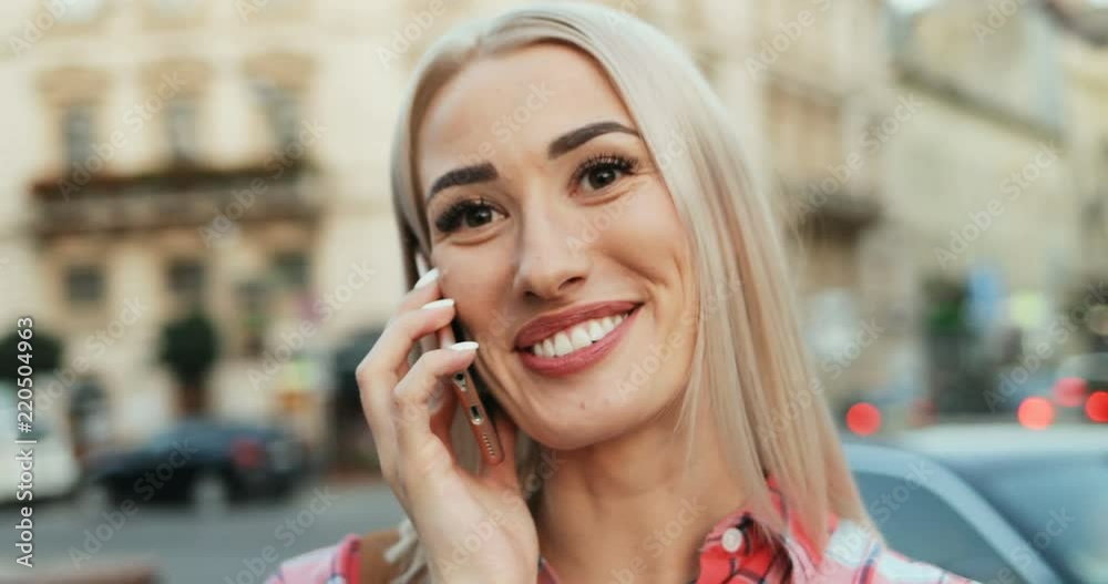 Close up of the beautiful cheerful blond woman laughing and talking on the phone outdoor. Close up of the beautiful cheerful blond woman laughing and talking on the phone outdoor.