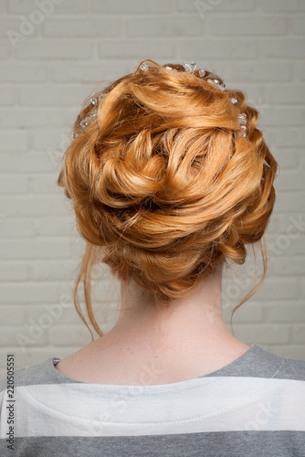 Professional female hairstyle on the head of a redhead girl.