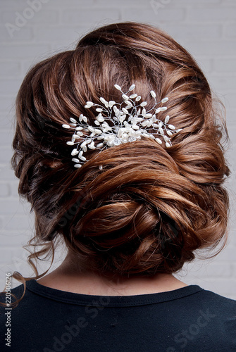 Female hairstyle is a high bunch on the head of a brown-haired woman at the back of a close-up.