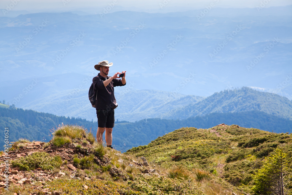 male hiker trekking and taking pictures in the mountains