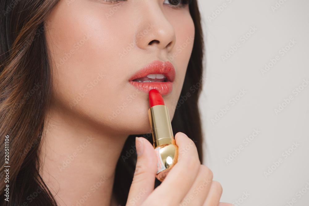 Young happy smiling woman applying lipstick, isolated over white background Young happy smiling woman applying lipstick, isolated over white background