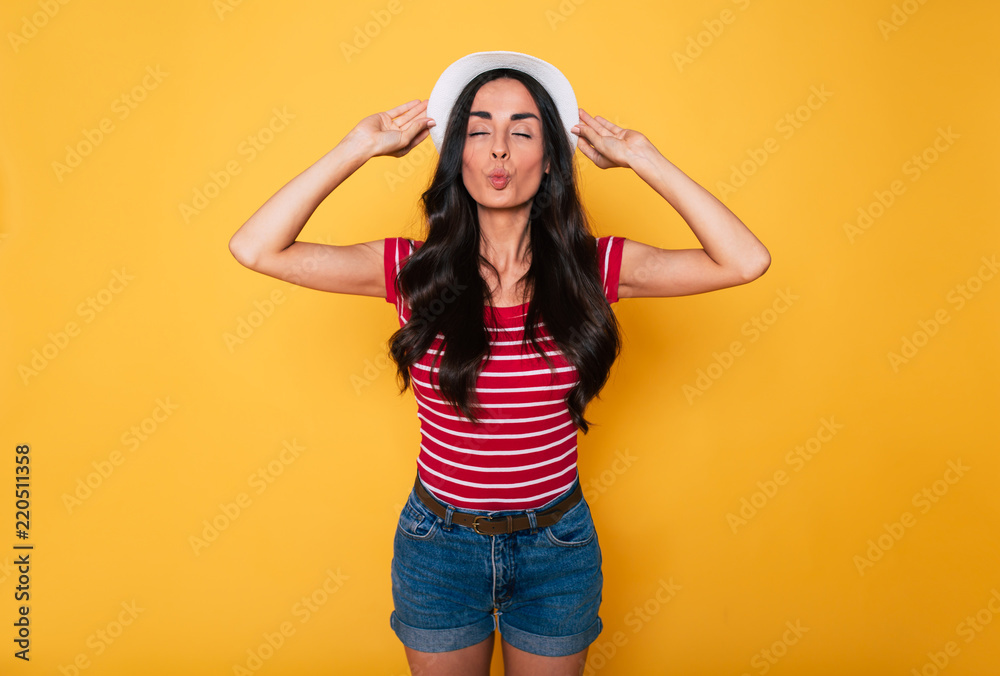 Send a kiss! Funny beautiful young hipster woman in hat posing over yellow background. Summer time Send a kiss! Funny beautiful young hipster woman in hat posing over yellow background. Summer time