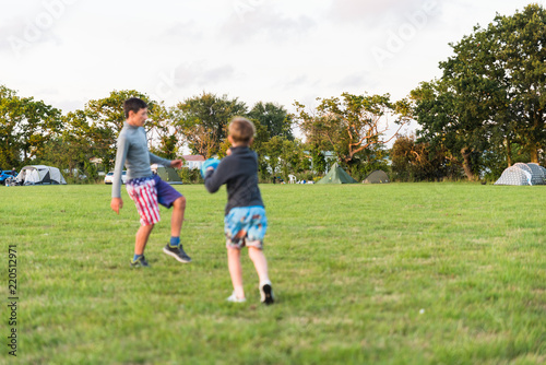 two brother boys not in focus playing with ball and having fun together over camping field in England