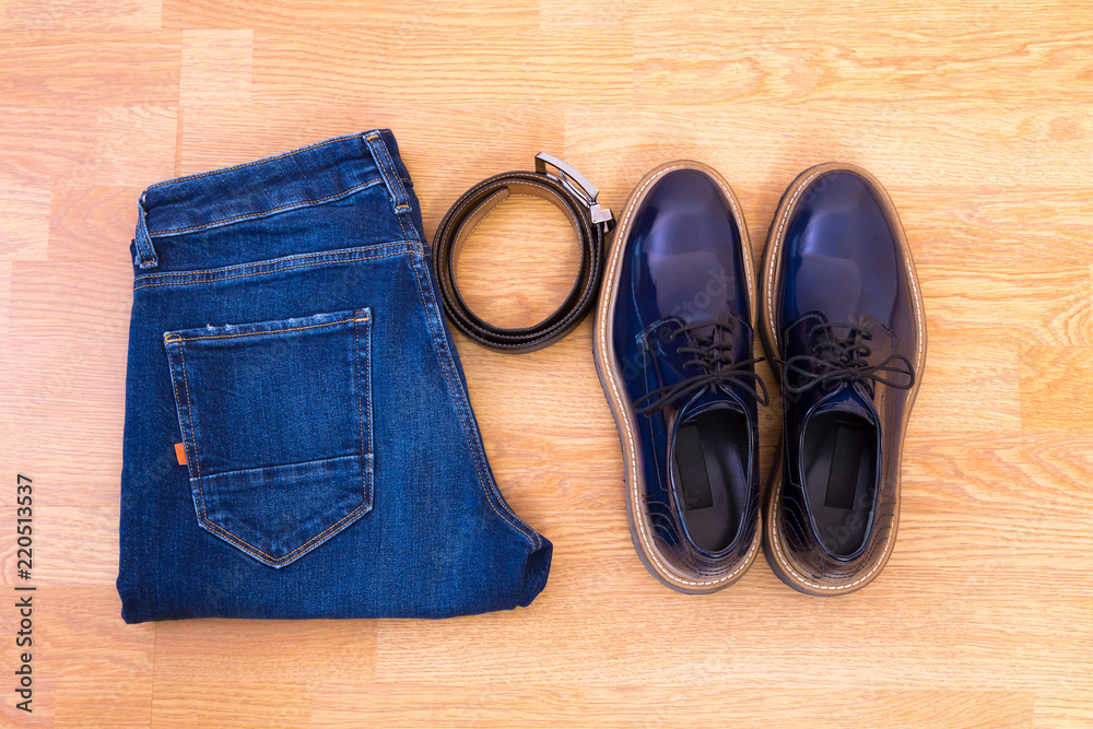 Men's jeans, leather belt and a pair of blue glossy shoes on wooden floor Men's jeans, leather belt and a pair of blue glossy shoes on wooden floor