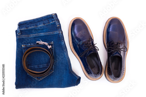 Men's jeans, leather belt and a pair of blue glossy shoes isolated on white background