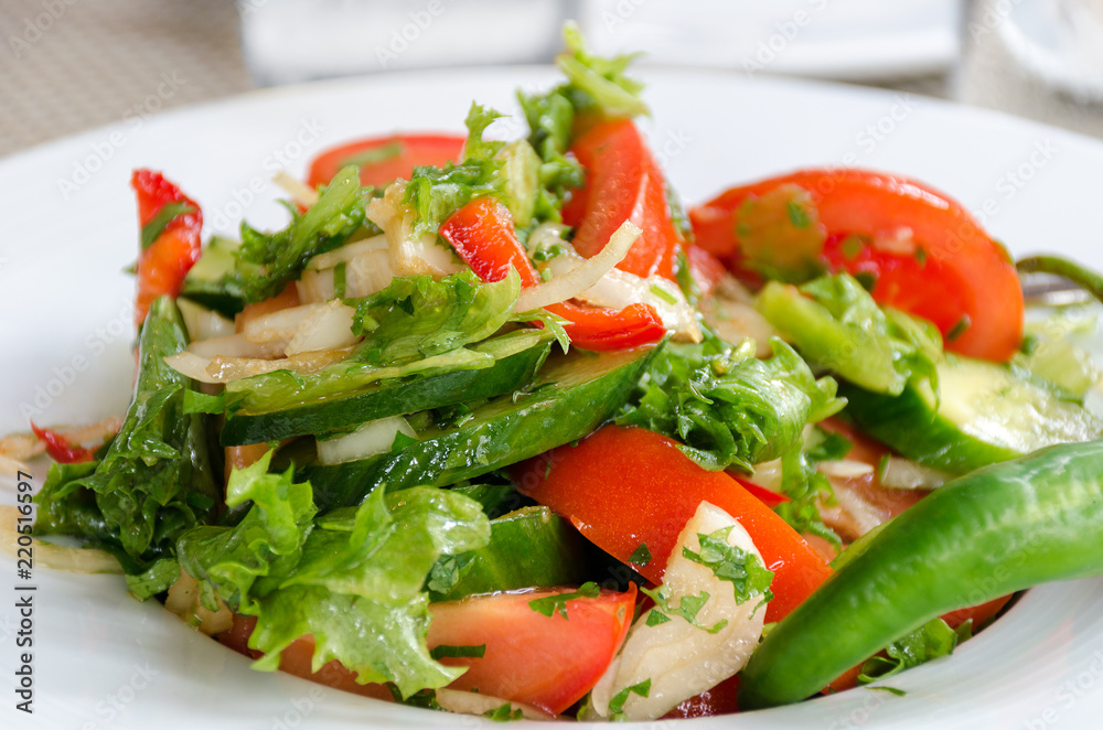 Healthy natural food, fresh salad with vegetables in plate - cucumbers, tomato, greens, close up. Shallow depth of field. Concept of vegetarianism, low calorie diet, weight loss, proper nutrition