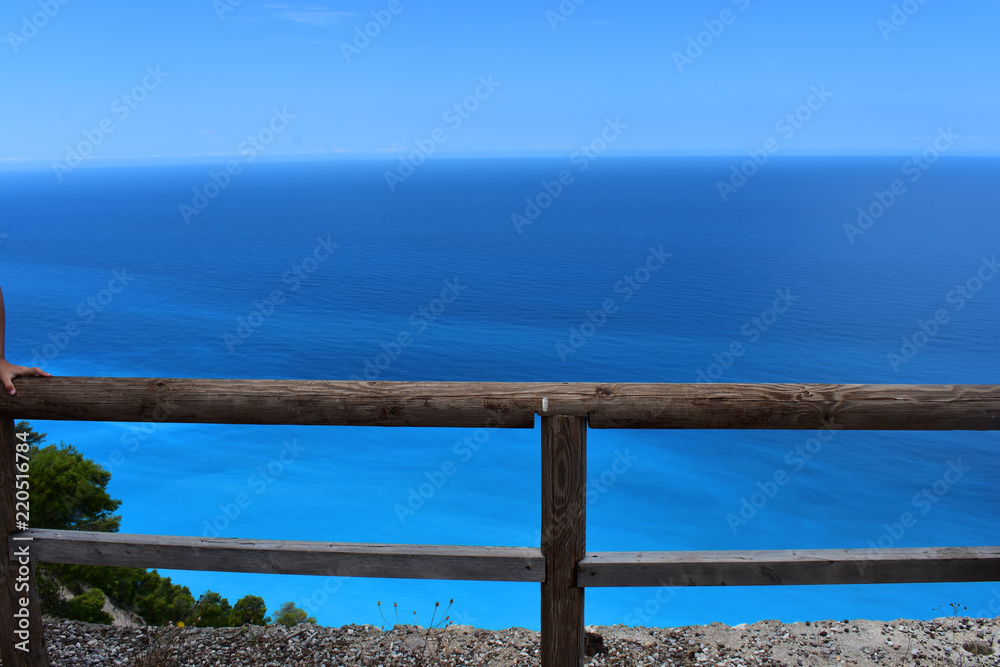a wooden fence with a blue sea in the background