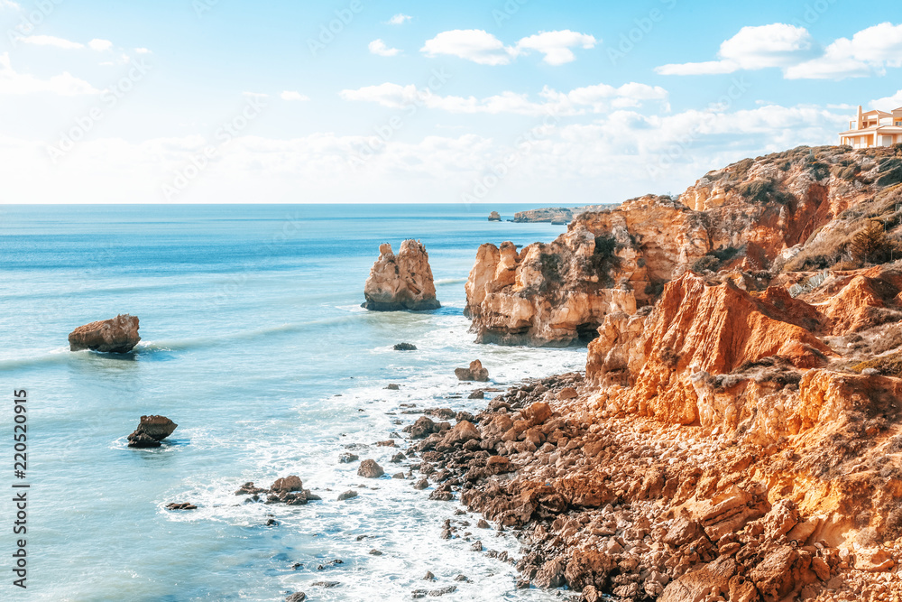 Panorama of Praia da Marinha on the south coast of Portugal in the Algarve on a sunny day. The cliffs, beach and Atlantic ocean are in view with tourists on the beach Panorama of Praia da Marinha on the south coast of Portugal in the Algarve on a sunny day. The cliffs, beach and Atlantic ocean are in view with tourists on the beach