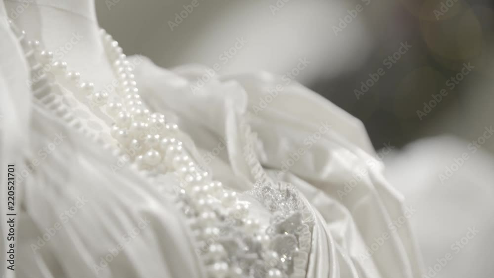 A white lacy dress on a female mannequin. Dettail of a wedding gown with necklace made of pearls. Fashion concept.