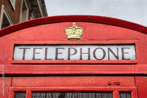 Traditional old style UK red phone box (booth) in London, England, United Kingdom - close up in cloudy weather