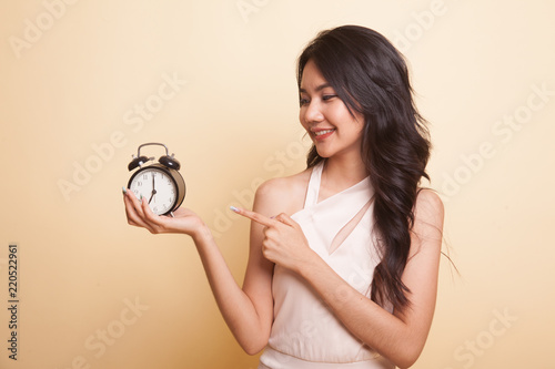 Young Asian woman point to a clock. © halfbottle