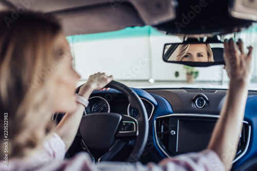 Photos woman adjusting the rear view mirror in car