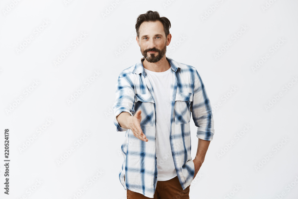 Nice to meet you, I am bachelor. Good-looking confident and friendly caucasian mature male with stylish haircut and beard, pulling hand towards camera in handshake, greeting business partner Nice to meet you, I am bachelor. Good-looking confident and friendly caucasian mature male with stylish haircut and beard, pulling hand towards camera in handshake, greeting business partner