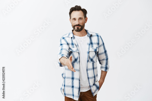 Nice to meet you, I am bachelor. Good-looking confident and friendly caucasian mature male with stylish haircut and beard, pulling hand towards camera in handshake, greeting business partner