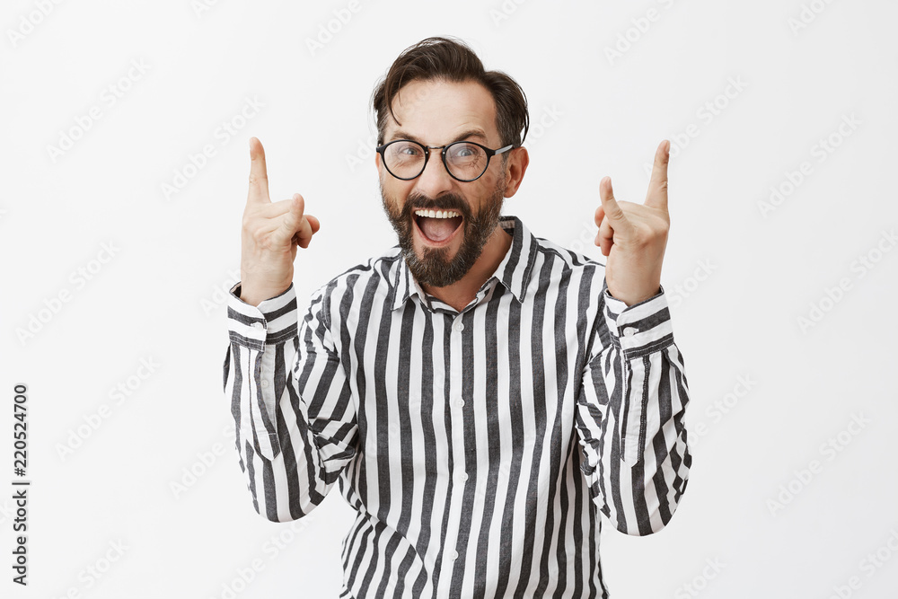 Heavy metal. Portrait of excited and thrilled attractive mature male with beard and moustache in glasses and striped shirt, showing rock sign and screaming from emotions, being on music festival Heavy metal. Portrait of excited and thrilled attractive mature male with beard and moustache in glasses and striped shirt, showing rock sign and screaming from emotions, being on music festival