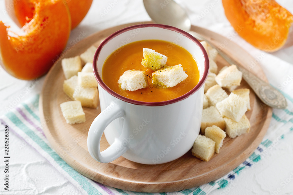 Delicate vegetable cream soup with pumpkin and croutons and slices of pumpkin on a light background. Delicate vegetable cream soup with pumpkin and croutons and slices of pumpkin on a light background.