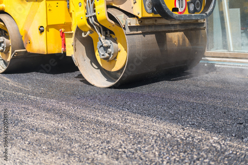 Roller drives over fresh asphalt and rolls the surface flat. © Philippe