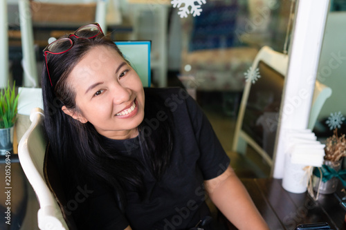 Happy middle ege asian woman with eye glasses smiling in cafe photo