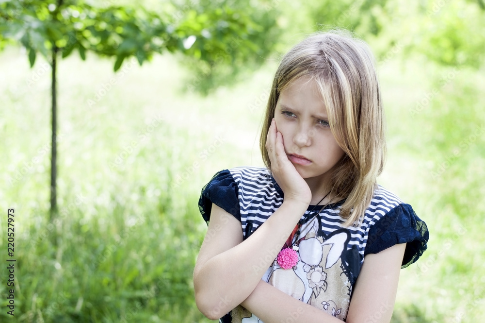 A sweet, sad young girl holds her cheek and regrets that she has a toothache. The girl suffers from pain in her teeth A sweet, sad young girl holds her cheek and regrets that she has a toothache. The girl suffers from pain in her teeth