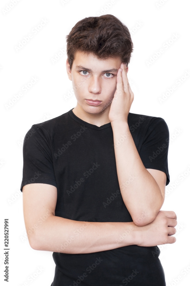 Sad teenager in a black T-shirt on a white background holds his head because he has a headache and a toothache Sad teenager in a black T-shirt on a white background holds his head because he has a headache and a toothache
