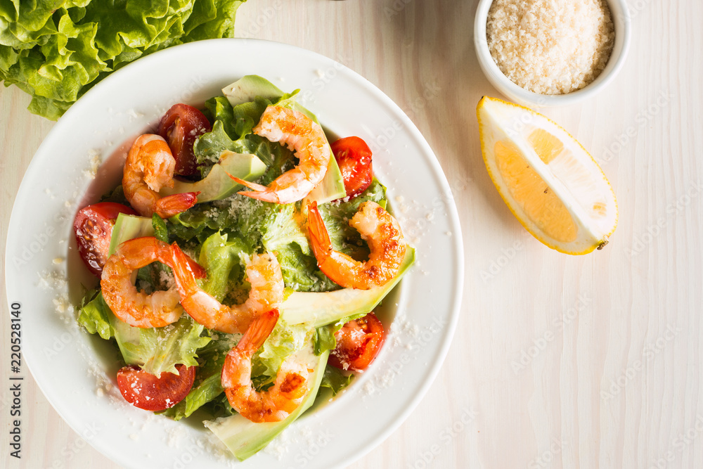 Fresh Caesar shrimp salad with delicious prawns, ruccola, spinach, cabbage, arugula, egg, parmesan and cherry tomato on wooden background. Oil, salt and pepper. Healthy and diet food concept. Fresh Caesar shrimp salad with delicious prawns, ruccola, spinach, cabbage, arugula, egg, parmesan and cherry tomato on wooden background. Oil, salt and pepper. Healthy and diet food concept.