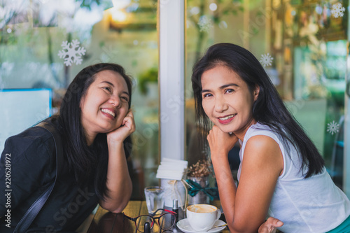 Two asian woman enjoy talking and drinking coffee in cafe