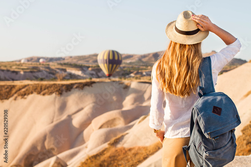 Hipster Traveler with backpack and outspread hands. Enjoying the view of the hot air balloons