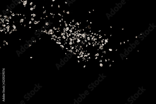 Tableau sur toile Split debris of stone exploding against black background.