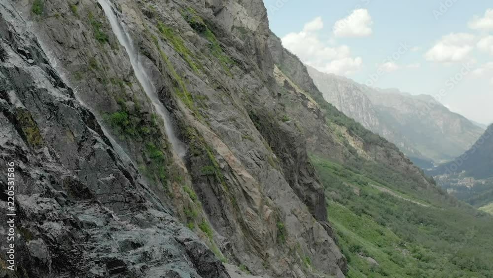 Tracking and top shot Air shot from a stream of water splashing waterfall on a rock wall in the Caucasus Mountains. Around the jet of the waterfall Tracking and top shot Air shot from a stream of water splashing waterfall on a rock wall in the Caucasus Mountains. Around the jet of the waterfall